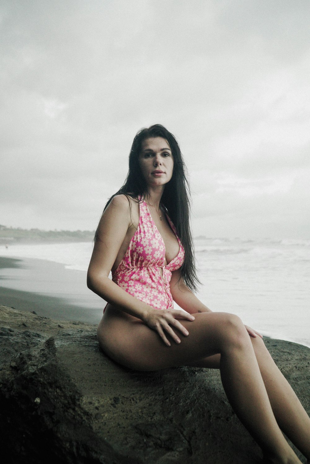 Una mujer sentada en una roca cerca del océano
