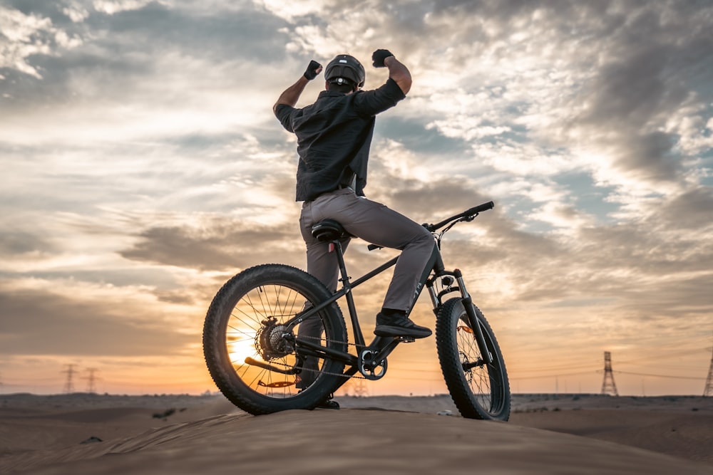 a man riding a bike on top of a sandy hill