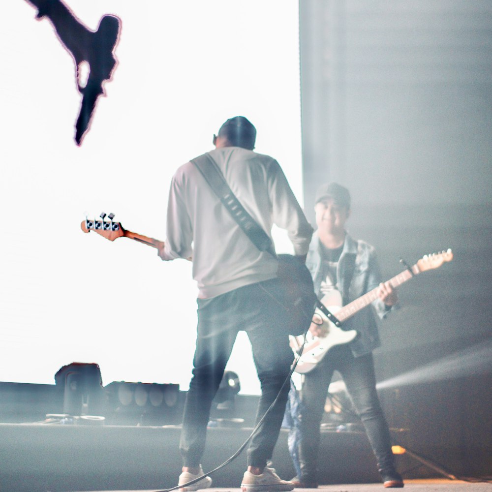 two men are playing guitars on a stage