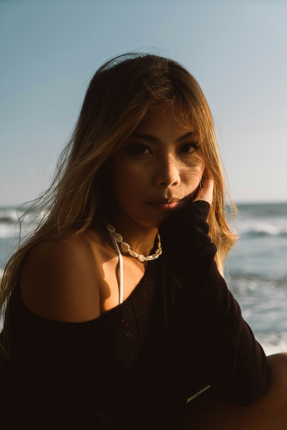 a woman sitting on a beach next to the ocean