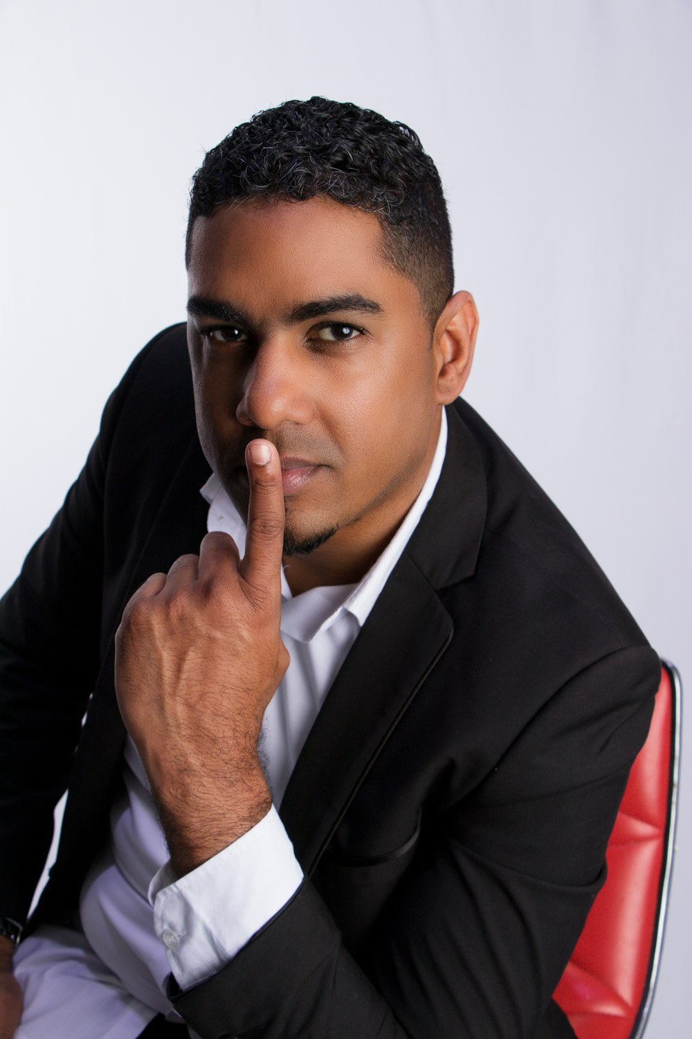a man in a suit sitting down and pointing his finger at the camera