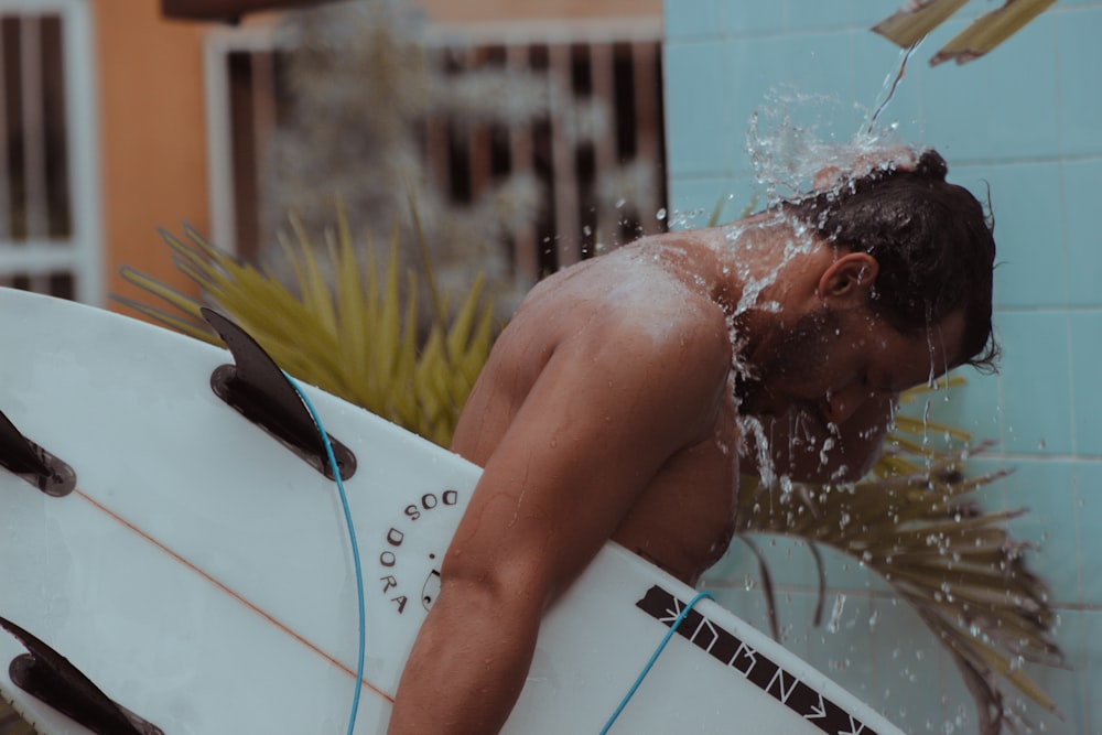 a man holding a surfboard under a shower of water