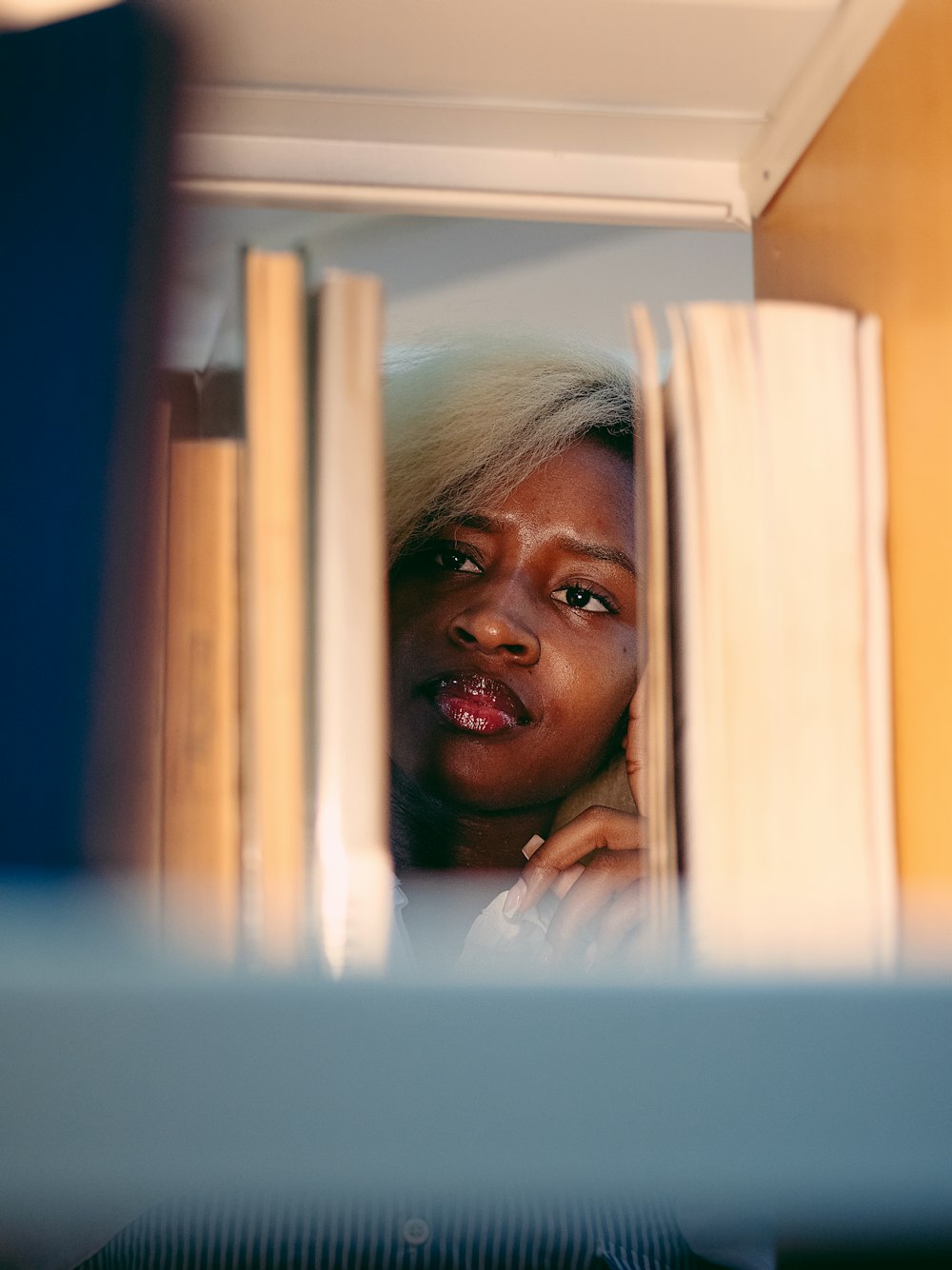 a woman looking out from behind a book shelf