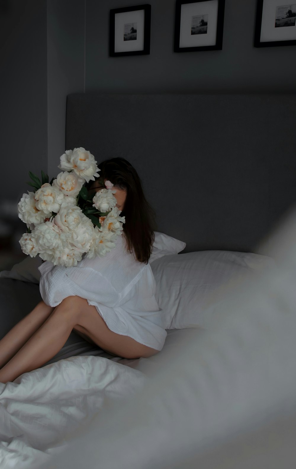 a woman sitting on a bed holding a bouquet of flowers