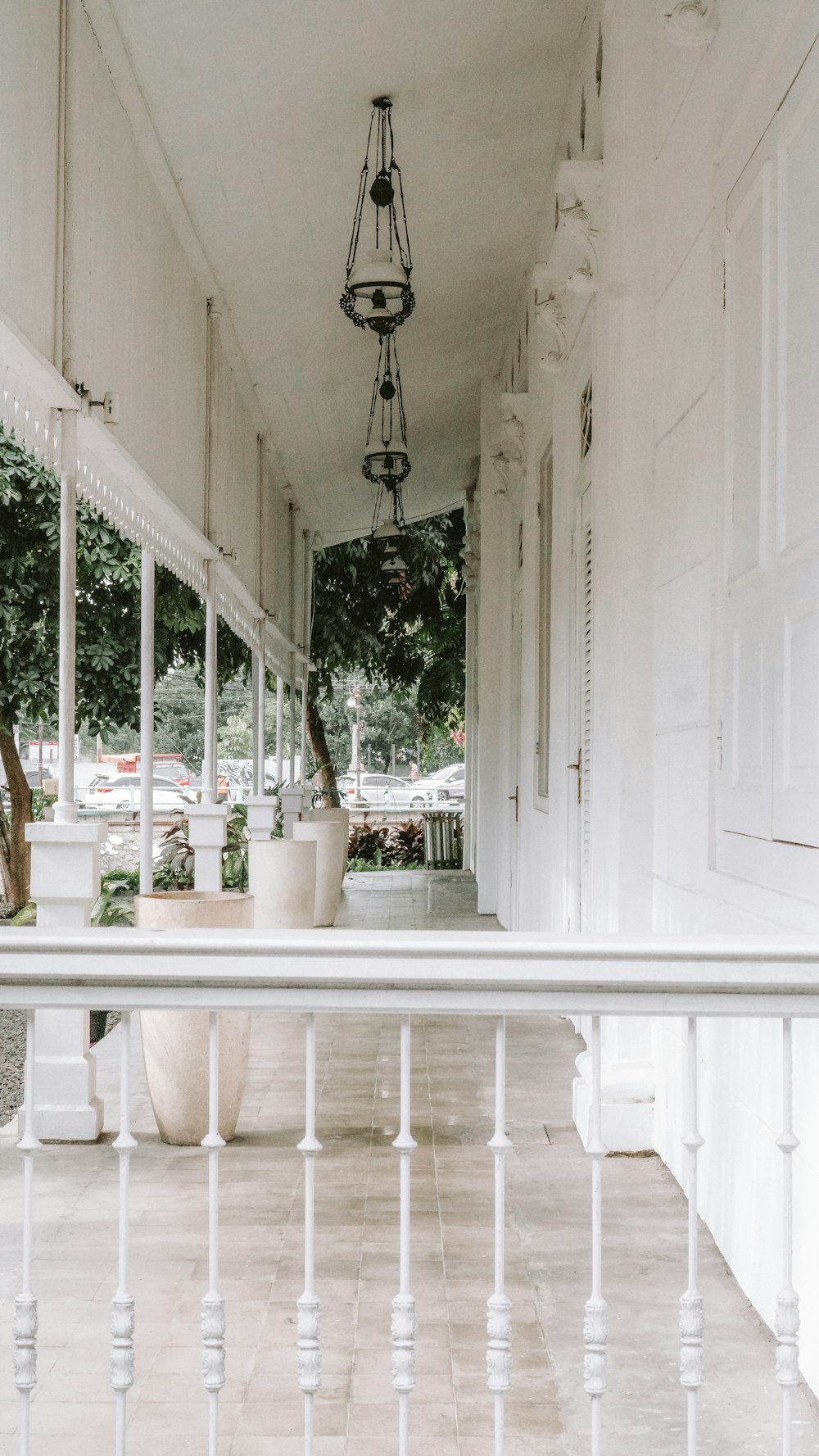 a porch with a white railing and potted plants