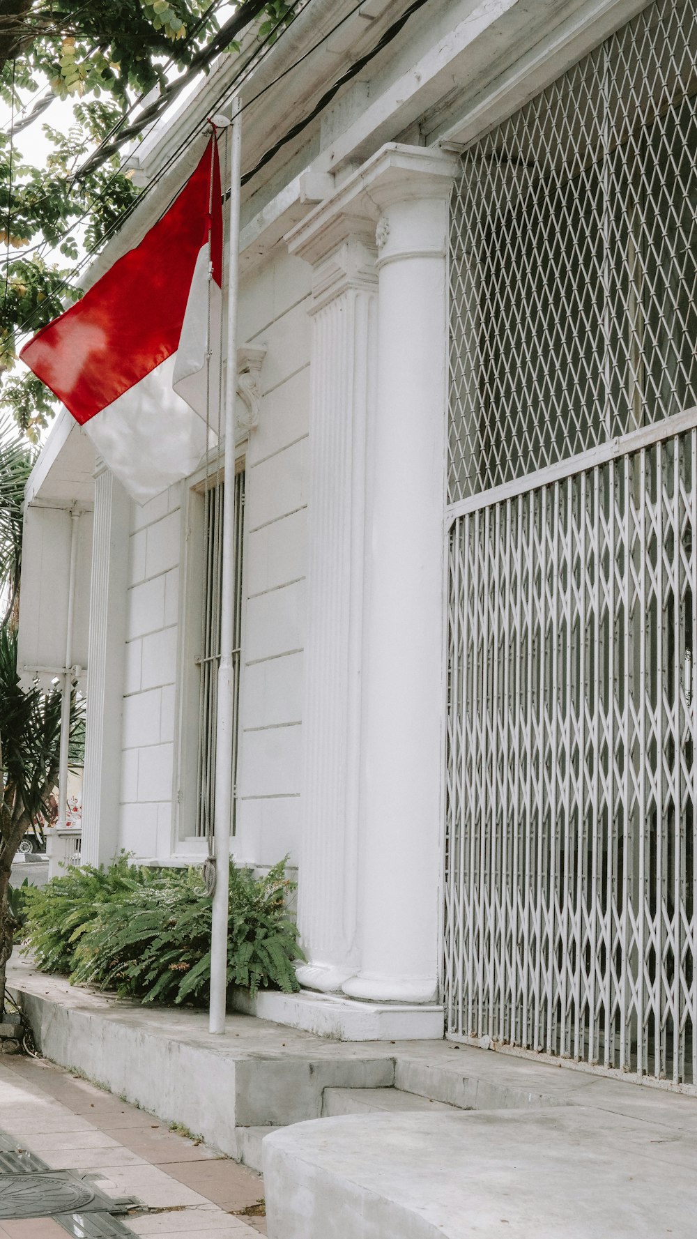 una bandera roja y blanca en un poste fuera de un edificio