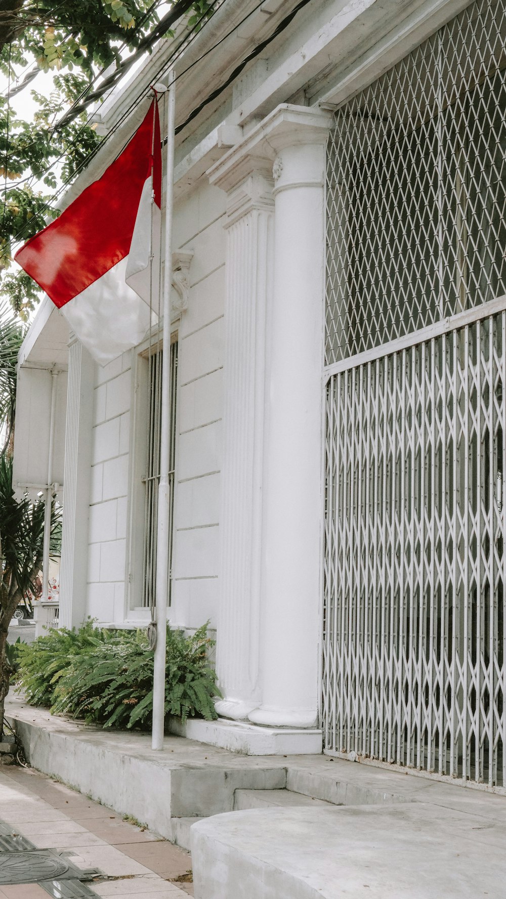 a red and white flag on a pole outside of a building