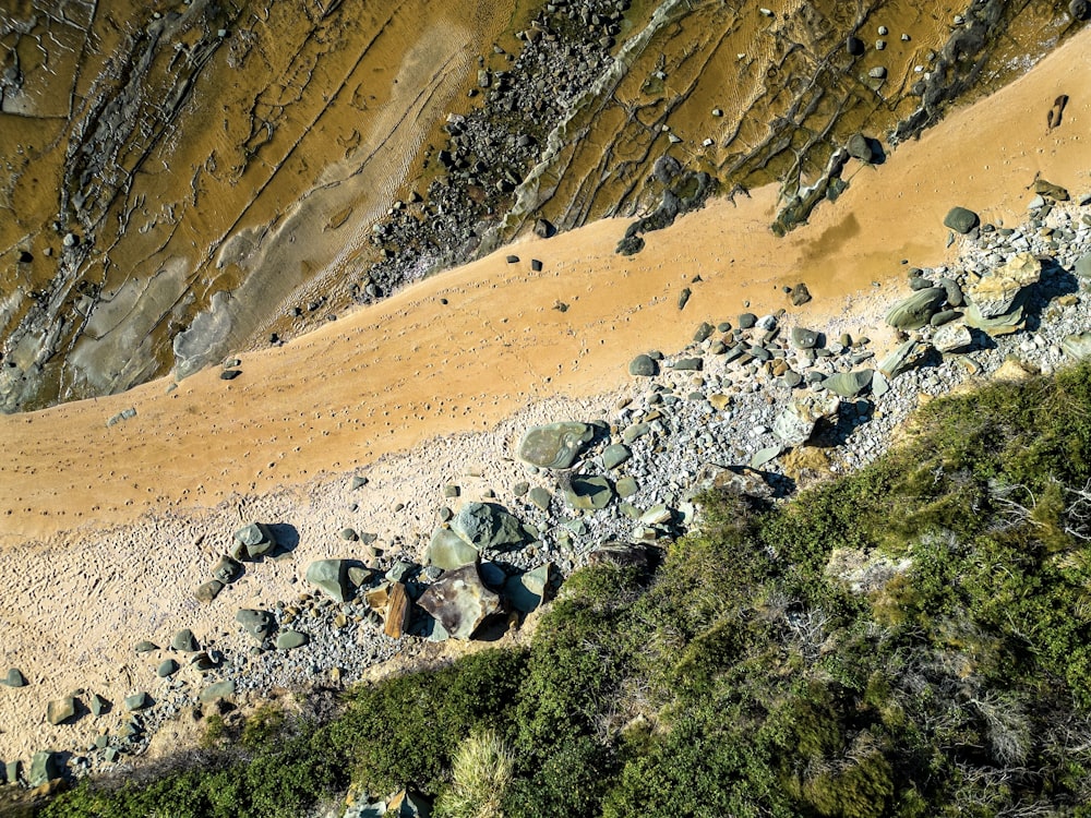 an aerial view of a sandy beach with rocks and grass