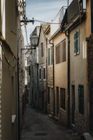 A quiet alleyway framed by old buildings with soft natural light filtering through.
