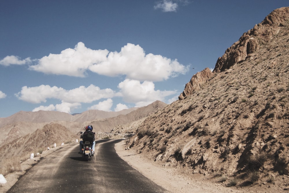 a man riding a motorcycle down a desert road