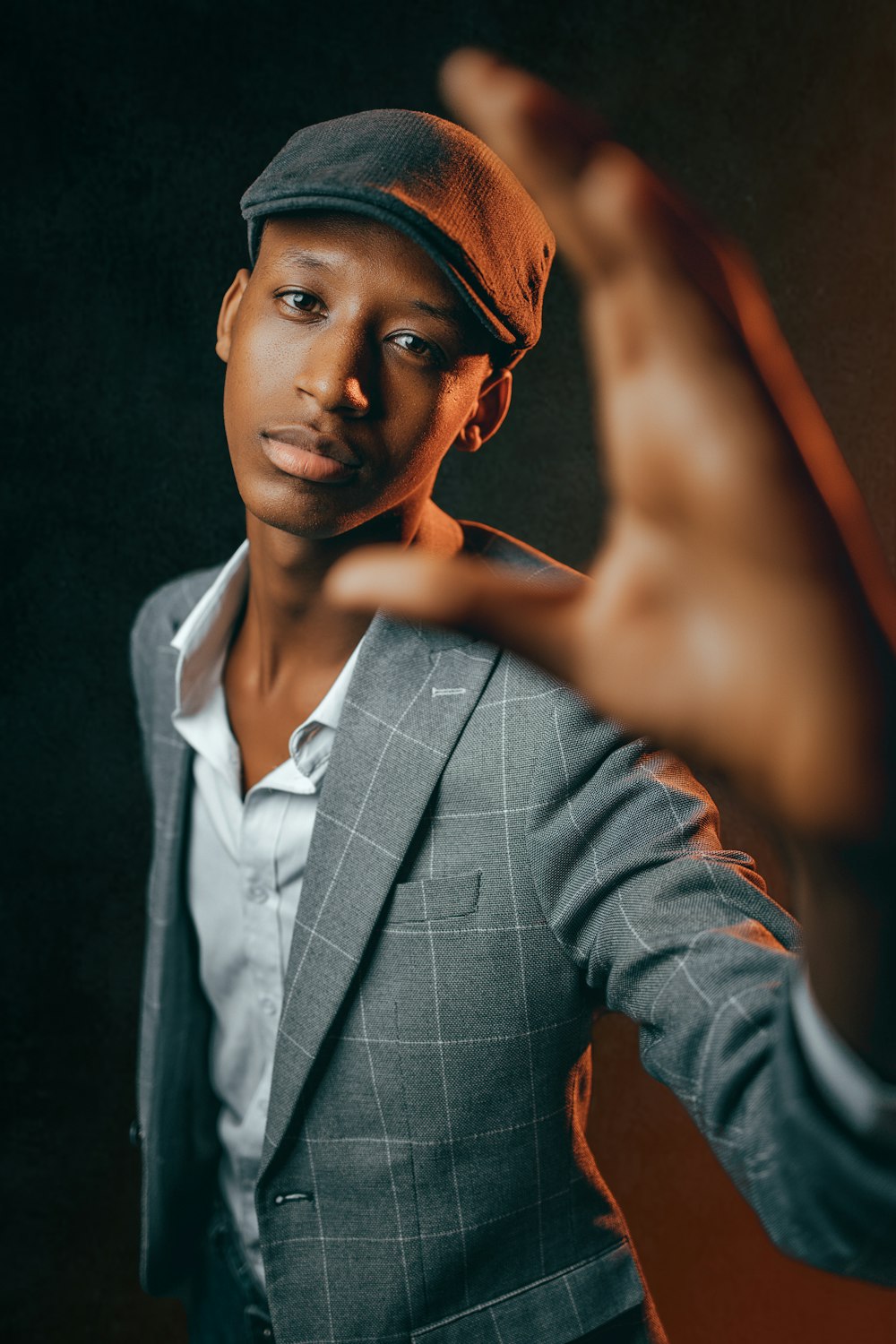 a man in a suit and hat making a hand gesture