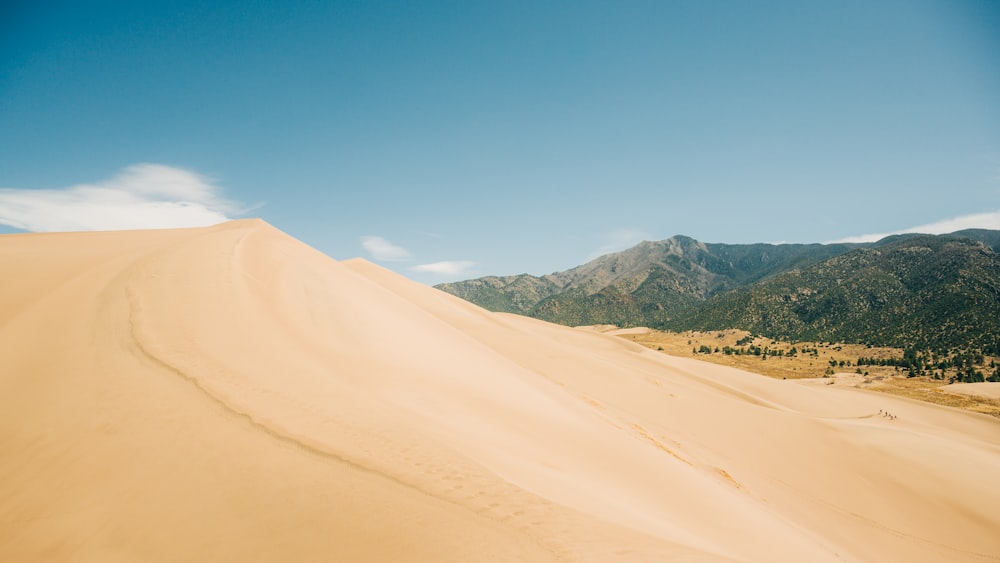 uma grande duna de areia com montanhas ao fundo