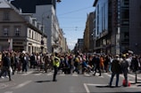 A vibrant street scene from a recent news event, bustling with people and colorful banners.