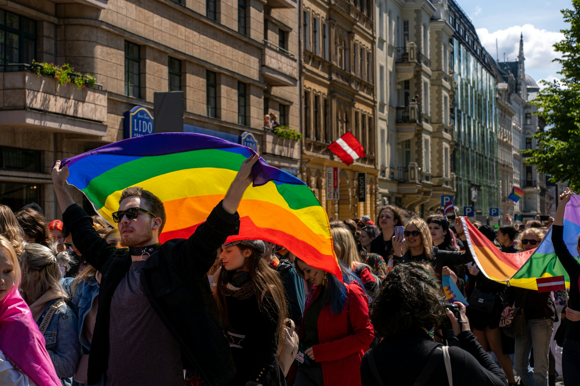 a man holding a rainbow colored kite in a crowd of people
