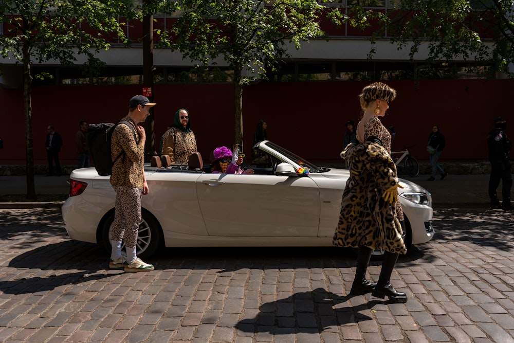 Una mujer parada junto a un coche descapotable blanco