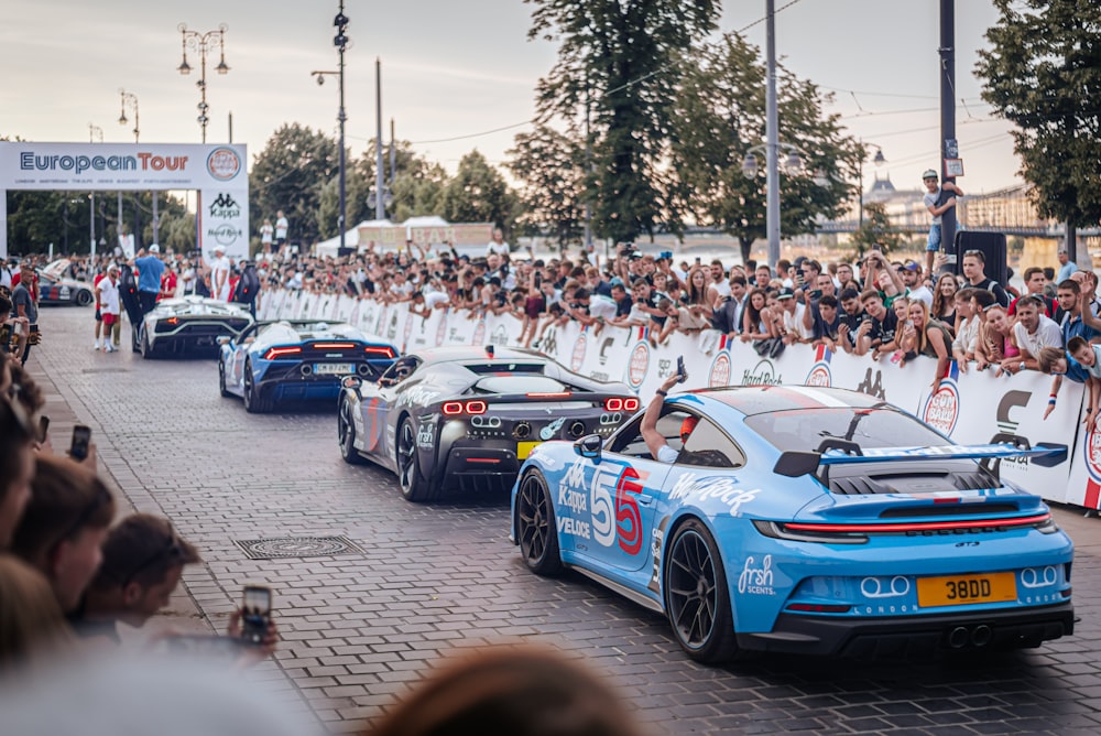 a group of cars driving down a street next to a crowd of people