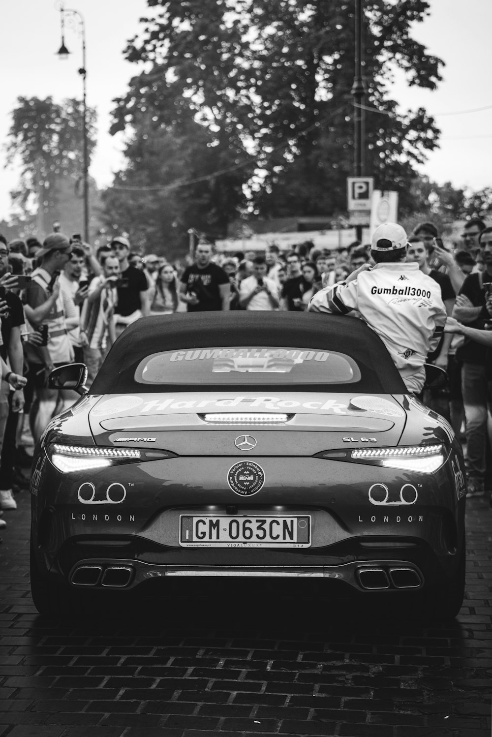 a black and white photo of a car in front of a crowd