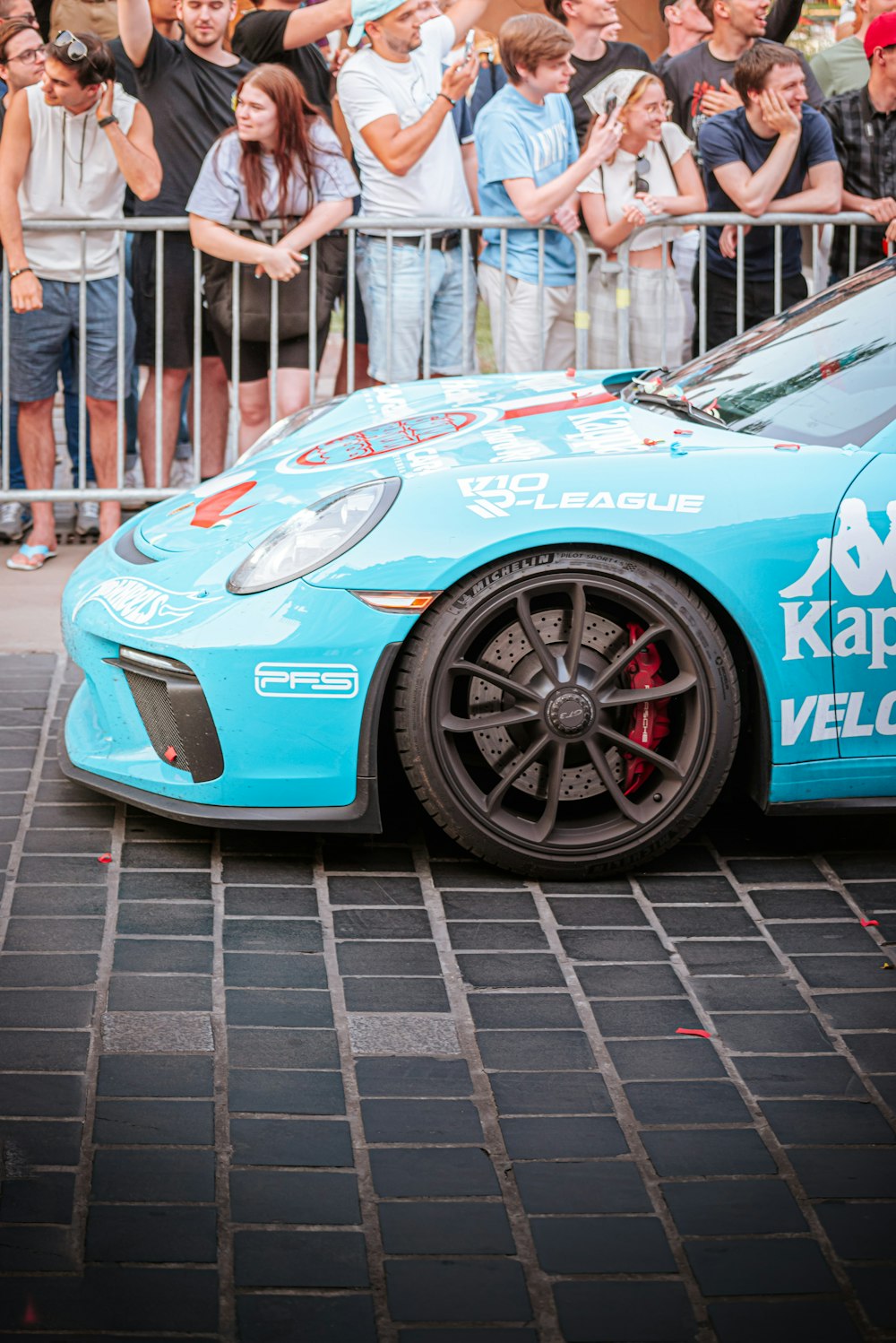 a blue sports car parked in front of a crowd of people