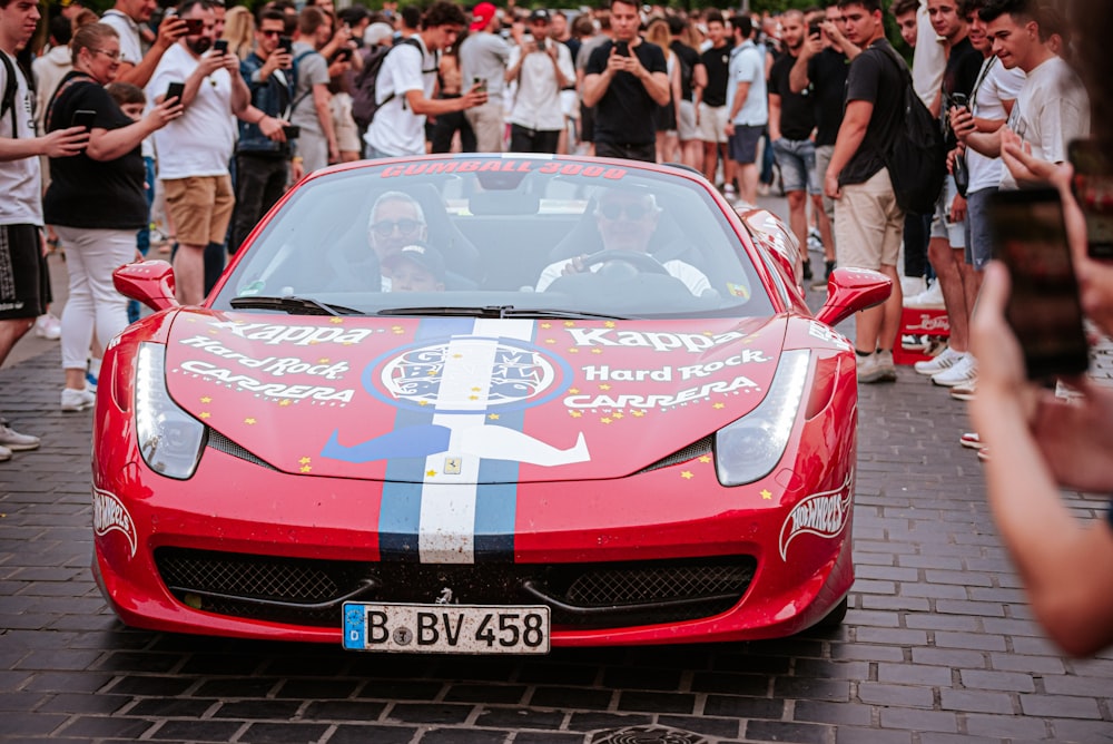 a red sports car parked in front of a crowd of people