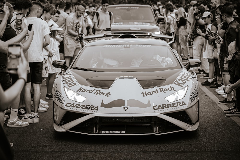 a sports car driving down a street surrounded by people