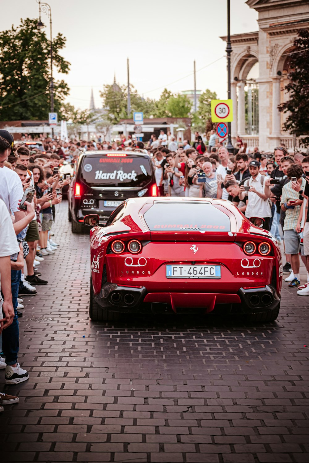 a red sports car driving down a street next to a crowd of people