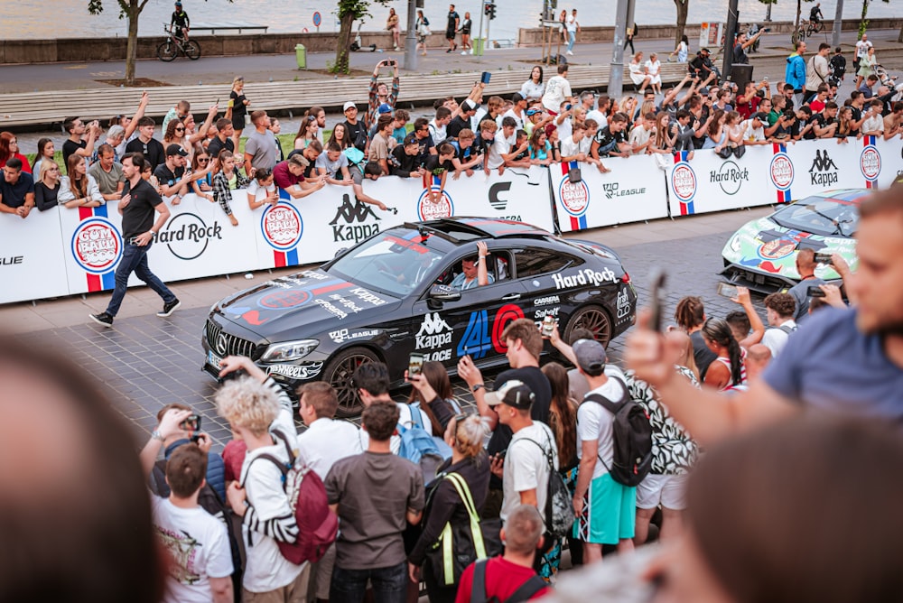 a crowd of people standing around a black car