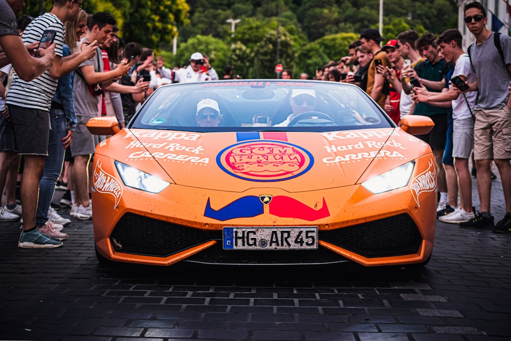 an orange sports car driving down a street