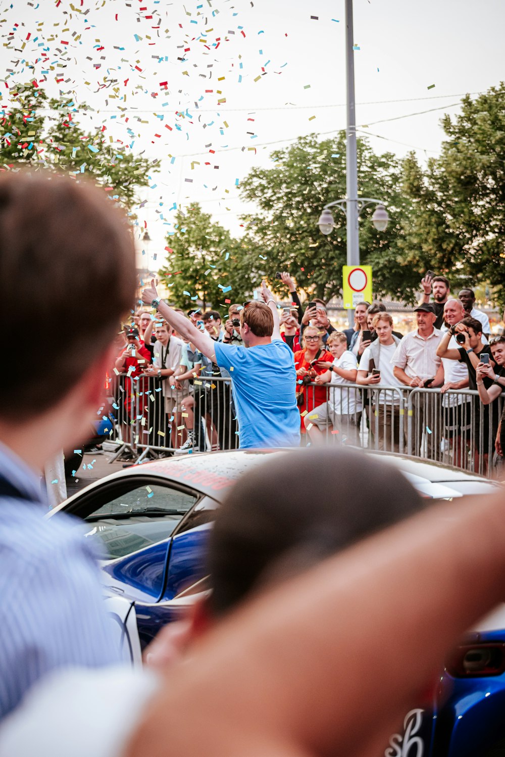 a crowd of people watching a parade with confetti in the air