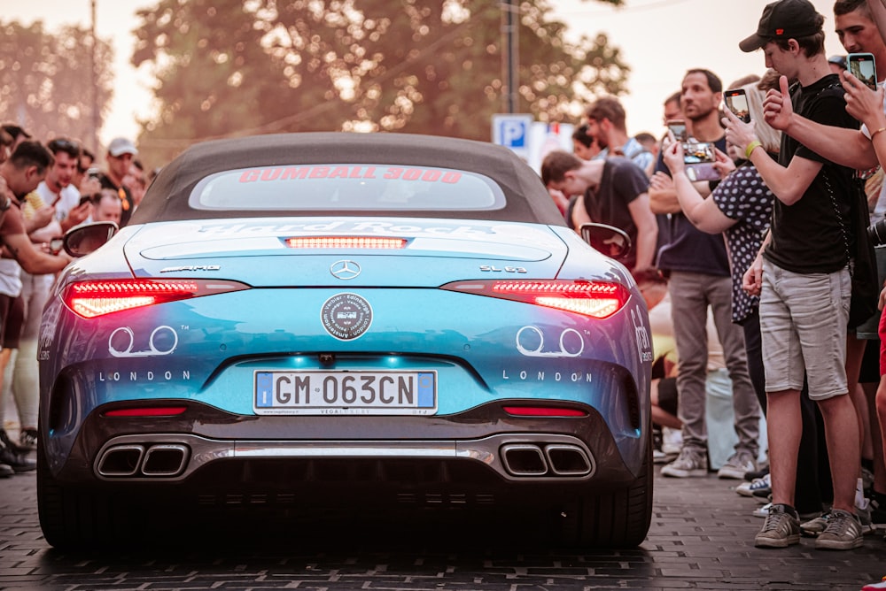 a blue sports car parked in front of a crowd of people