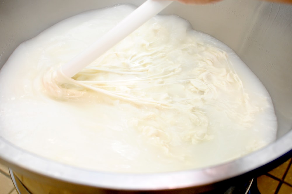 a person stirring a bowl of milk with a spatula