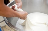 Close-up of hands gently churning fresh curd in a traditional wooden bilona churner.