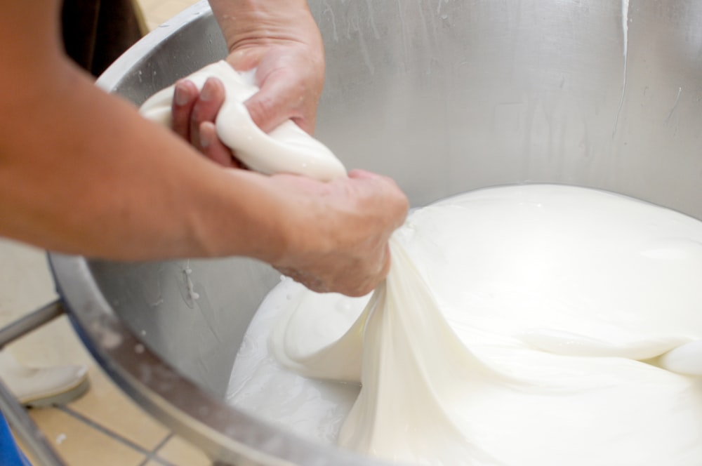 a person is kneading dough in a metal bowl