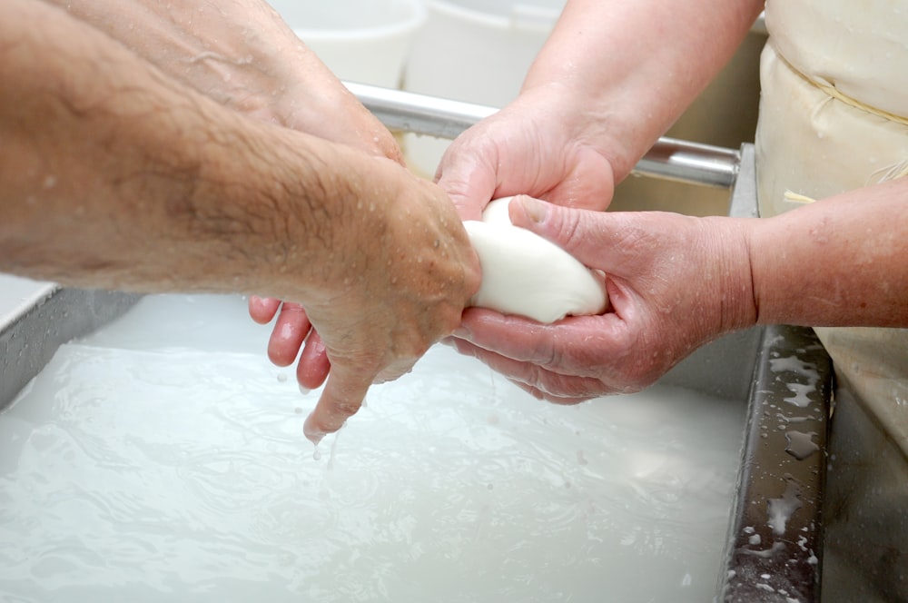 two people are washing their hands in a sink