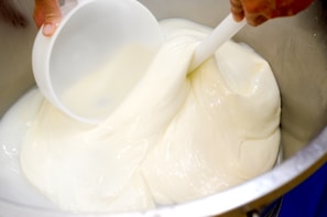 a person mixing a mixture in a metal bowl