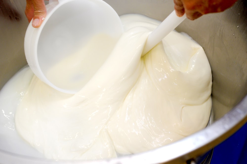 a person mixing a mixture in a metal bowl