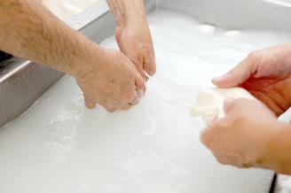 two people are washing their hands in a sink