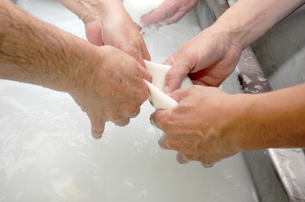 a group of people washing their hands in a sink