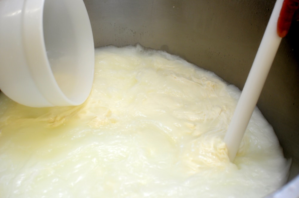 a large pot filled with white liquid with a plastic spoon sticking out of it