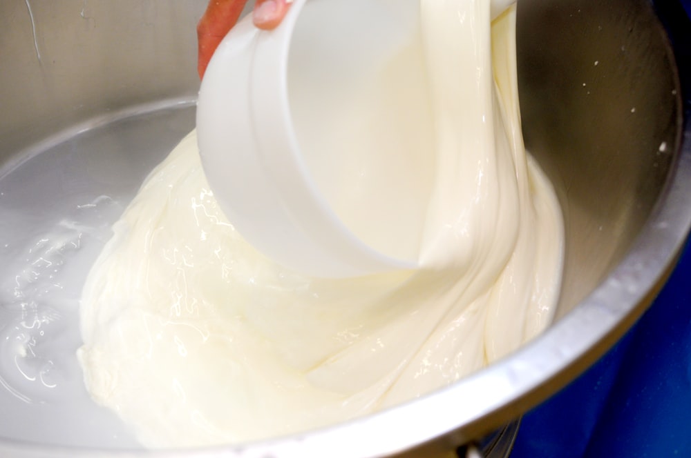 a person pouring batter into a metal bowl