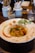 A vibrant plate of freshly made pasta topped with herbs and sauce, set on a rustic wooden table.