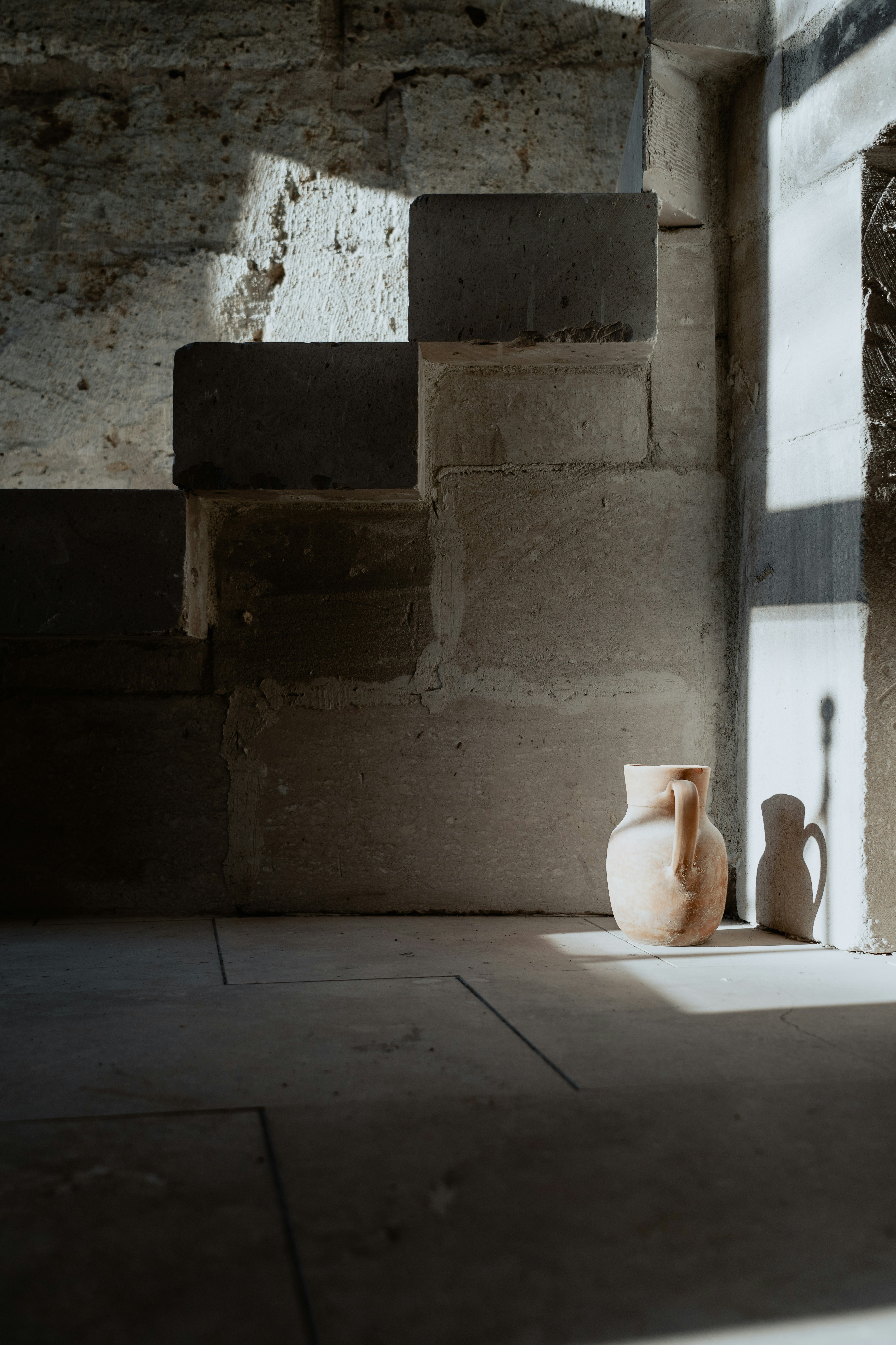 a white vase sitting on top of a cement floor