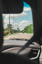 A dashboard view of a car driving on a highway with clear skies.