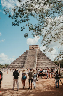 A vibrant sunset over the ancient pyramid of Chichén Itzá with tourists admiring the view.