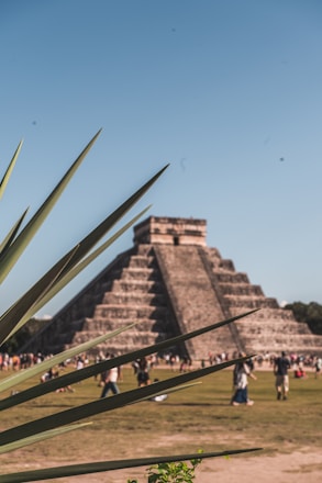 An aerial view of a large pyramid-shaped structure surrounded by greenery and people.