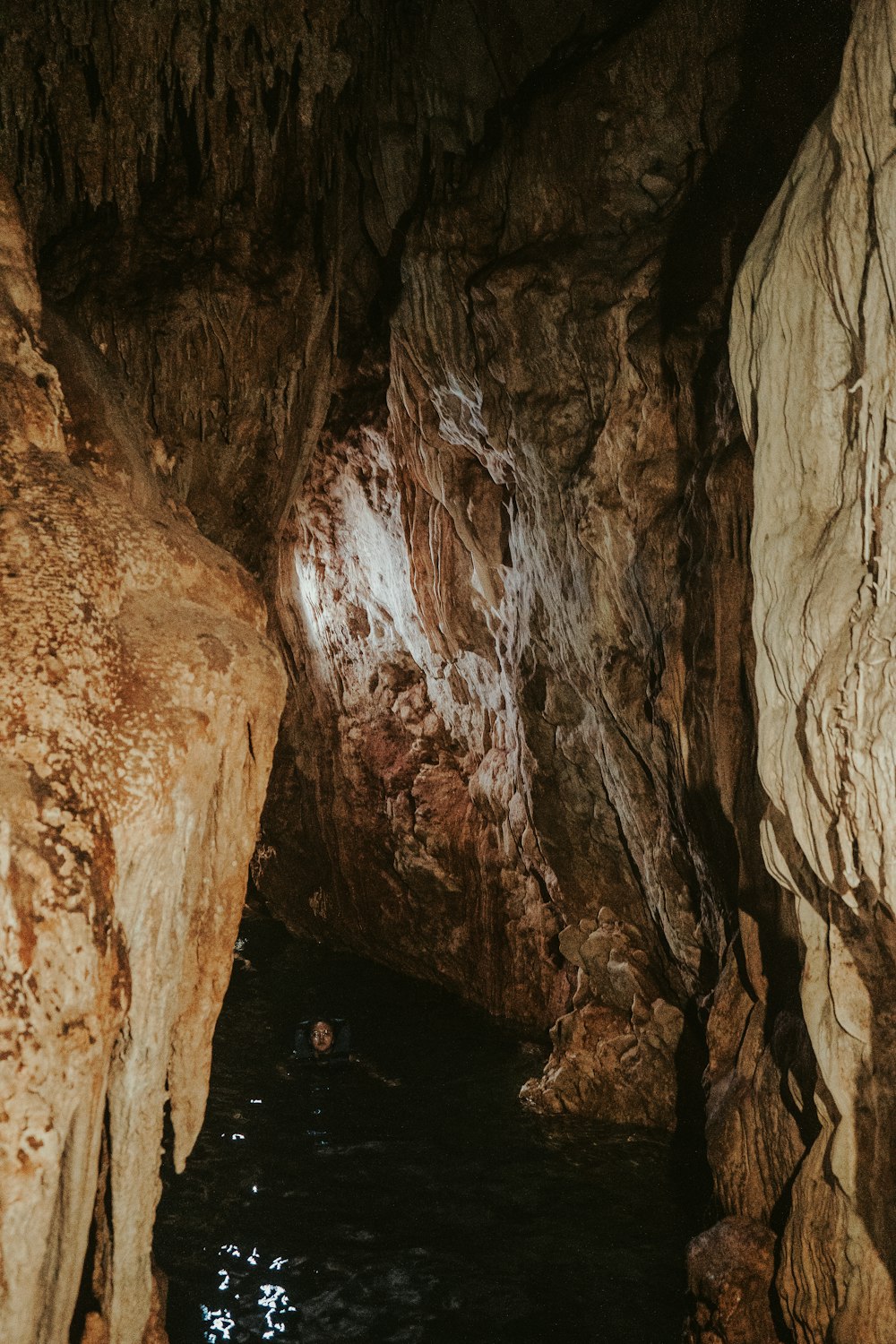 a person swimming in a pool of water in a cave