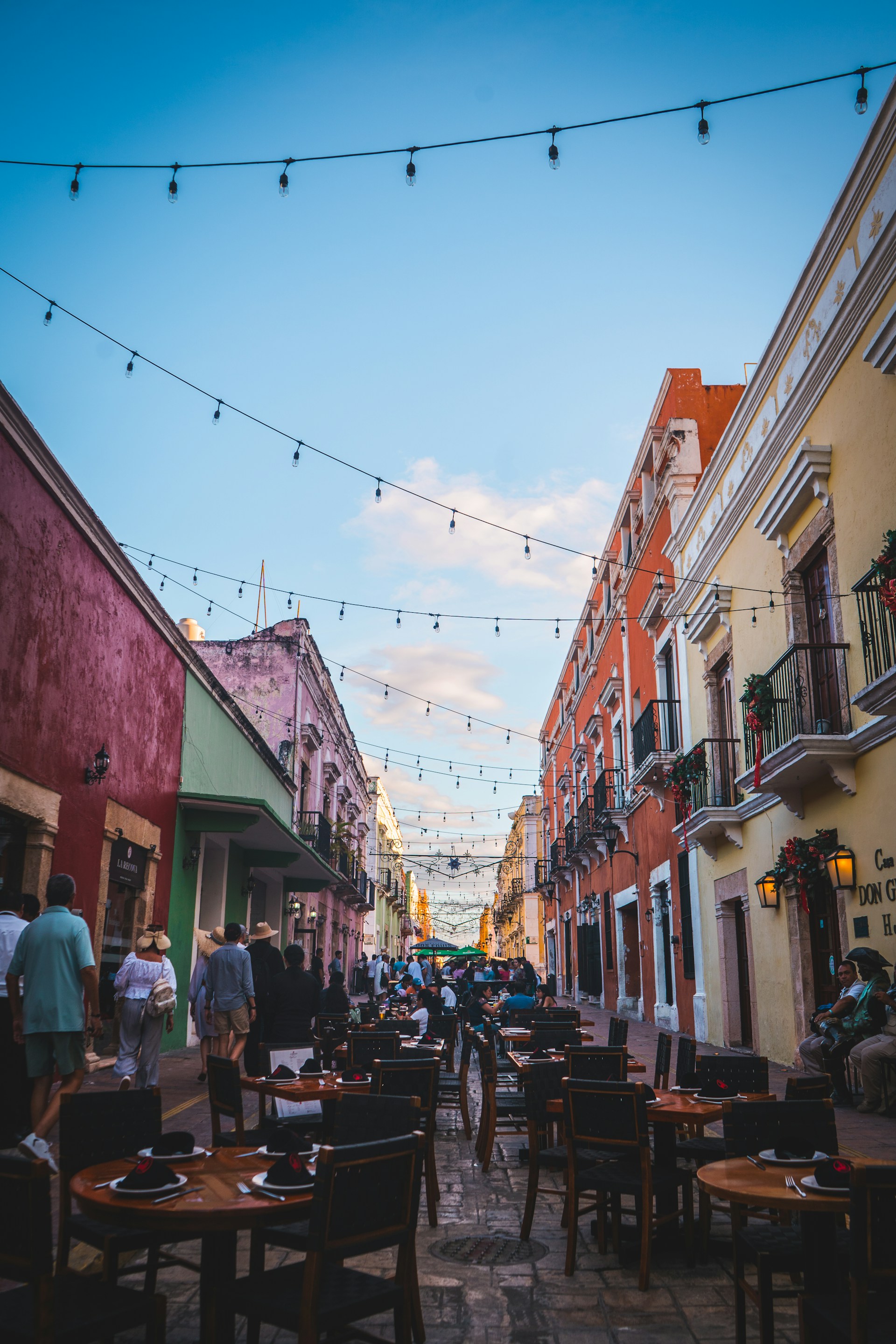 A vibrant street scene featuring a bustling outdoor dining area with colorful tables and chairs.