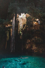 Sunlight streaming into the turquoise waters of Cenote Suytun, surrounded by lush jungle.