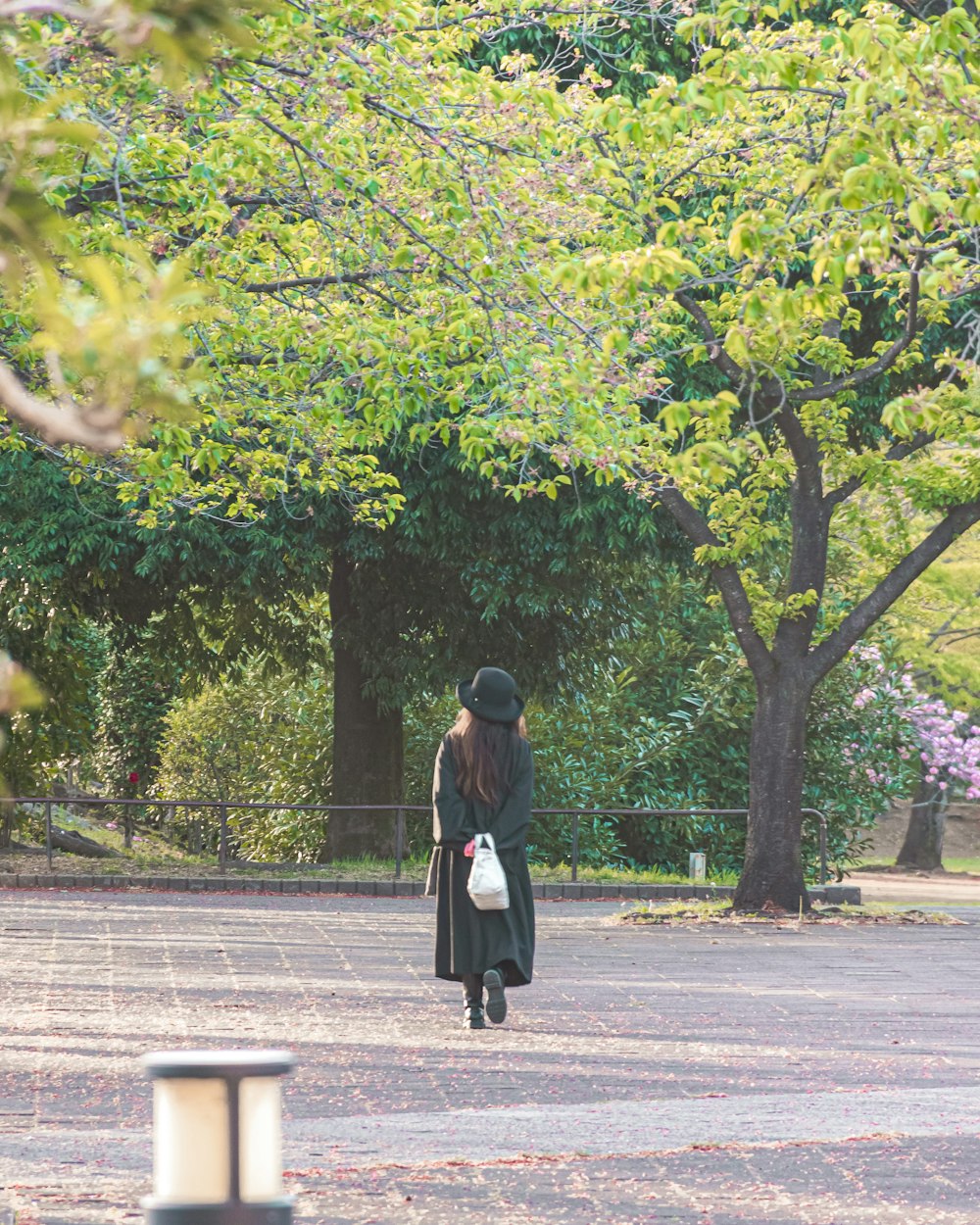 a woman walking down a street in a park