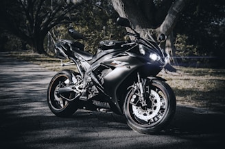 A sleek Yamaha motorcycle parked in front of the Yamaha Tasikmalaya dealership with bright morning light highlighting its details.