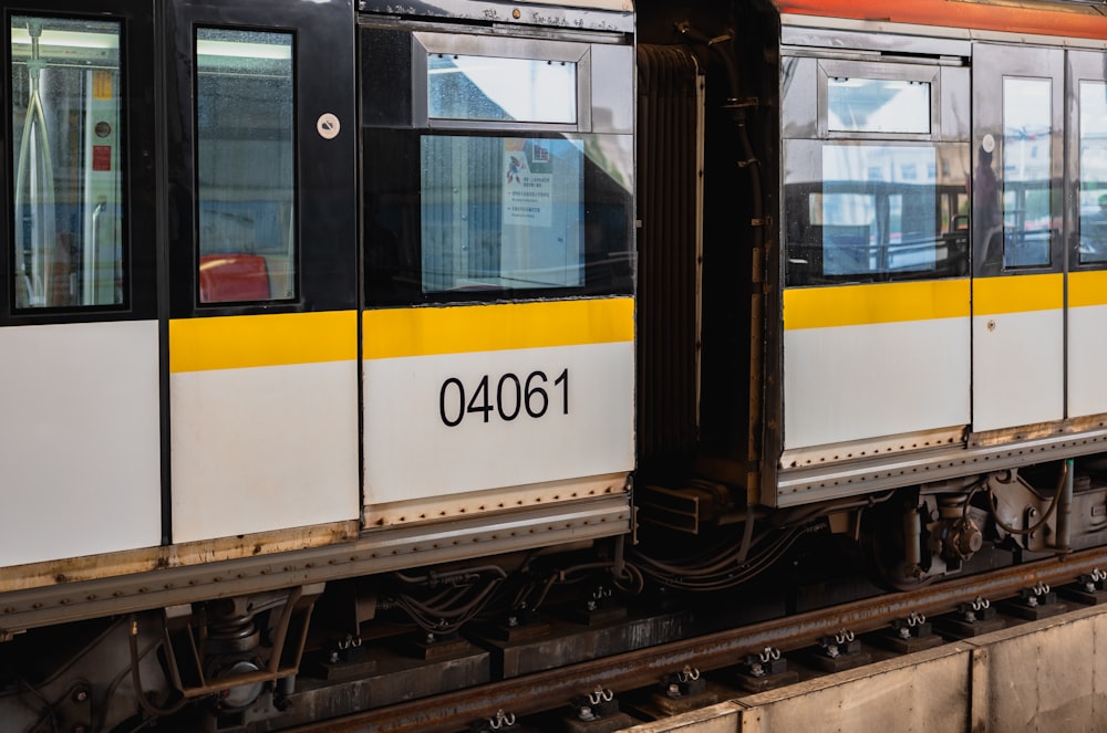 a yellow and white train is on the tracks